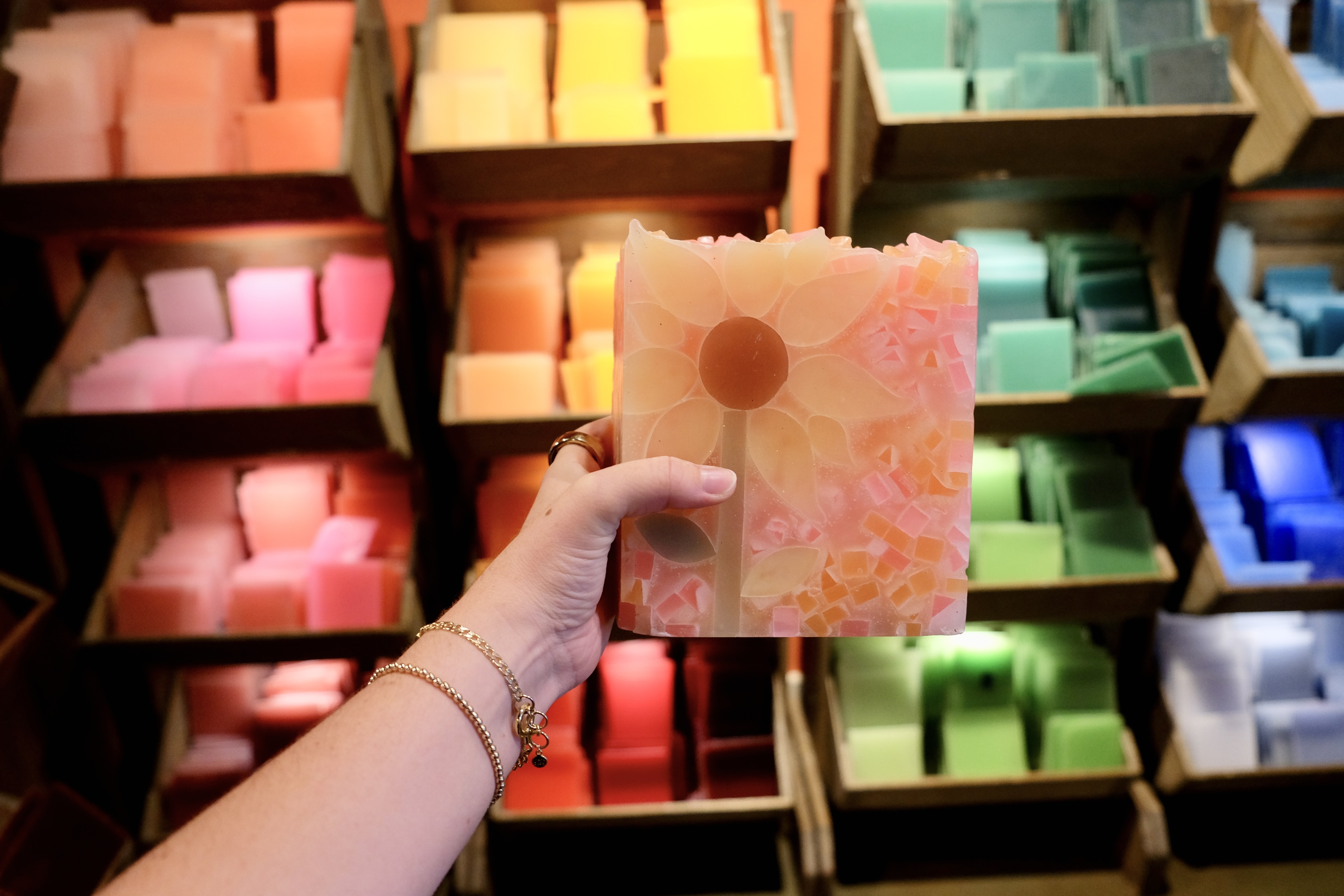 Pink mosaic wax piece held up in front of colorful wax display at Glow Candle Lounge