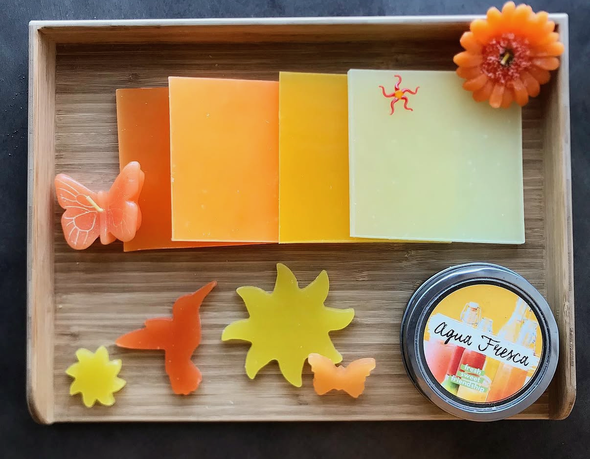 A tray of colorful handmade candles and fragrance pieces at Glow Candle Lounge