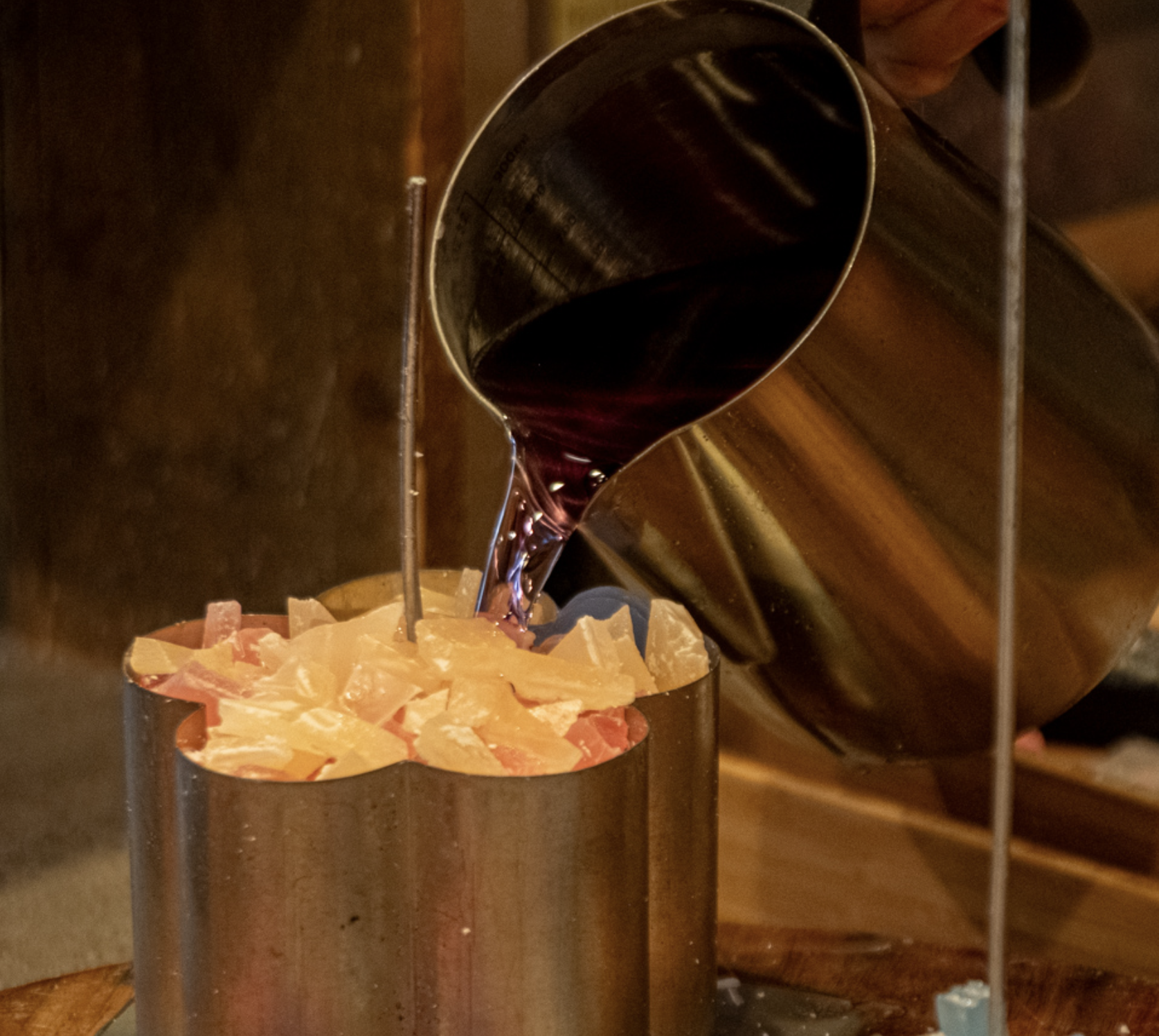 Pouring warm wax into a candle mold at Glow Candle Lounge